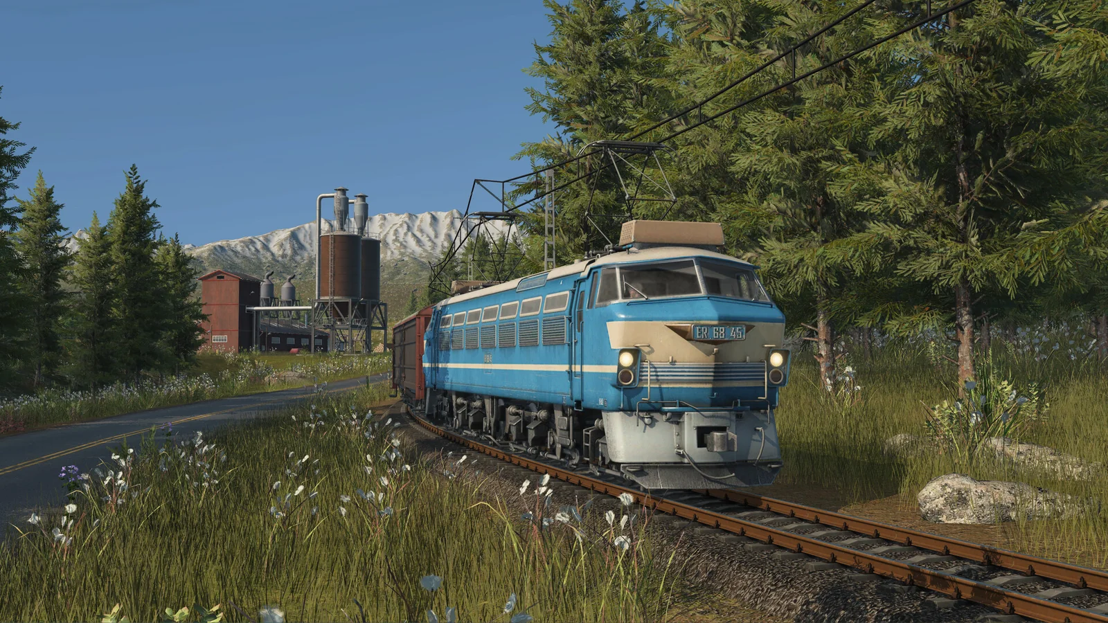 Blue freight locomotive passing an industrial railway in Transport Fever 3